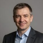 Профессиональный портрет уверенного бизнесмена с дружелюбным взглядом на размытом нейтральном фоне студии